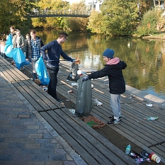 Das Foto zeigt Studierende, die mit Papierzangen und Abfallsäcken die Lahnterrassen von Müll befreien. © Universitätsstadt Marburg, Ute Schneidewindt