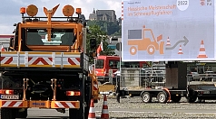 Das Foto zeigt ein Räumfahrzeug und das offizielle Plakat der Meisterschaften. Dazwischen thront das Landgrafenschloss auf seinem Schlossberg.